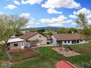 Back of house with a yard, a patio, fence, and a mountain view