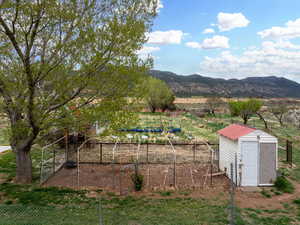 View of yard with a storage unit, an outbuilding, fence, and a mountain view