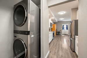 Laundry area with light wood-type flooring, stacked washer and dryer, and laundry area