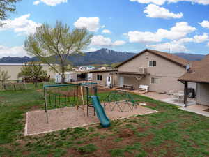 View of play area with a lawn, a patio, a mountain view, and central AC unit