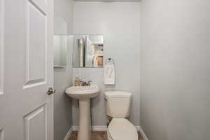 Half bath with toilet, tile patterned floors, a sink, and baseboards