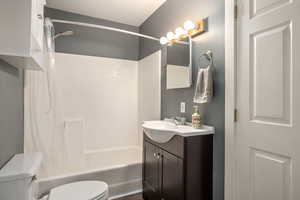 Bathroom featuring shower / bath combination with curtain, vanity, and toilet