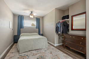 Bedroom featuring baseboards, wood finished floors, and ceiling fan