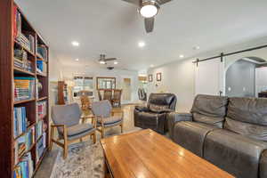 Living room with a barn door, a ceiling fan, wood finished floors, and recessed lighting