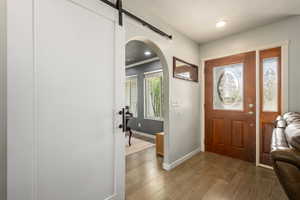 Foyer with a barn door, recessed lighting, wood finished floors, arched walkways, and baseboards