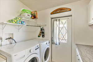 Clothes washing area featuring cabinet space and washer and clothes dryer