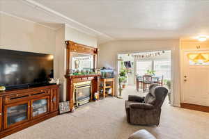 Living room featuring a fireplace, ornamental molding, tile patterned flooring, carpet flooring, and lofted ceiling