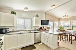 Kitchen featuring dishwasher, a sink, a peninsula, black microwave, and vaulted ceiling