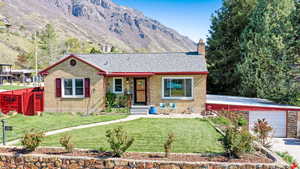 Ranch-style home with a mountain view, driveway, a chimney, brick siding, and a front yard