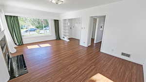 Living room featuring baseboards, wood finished floors, visible vents, and a fireplace