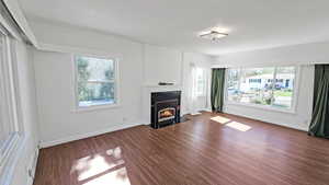 Living room with a tiled fireplace, baseboards, and wood finished floors