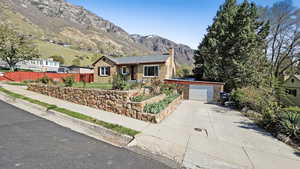 Single story home featuring a mountain view, fence, stone siding, and driveway