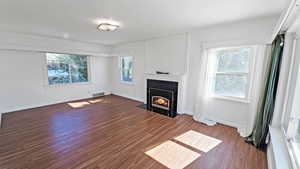 Living room featuring a wealth of natural light, wood finished floors, a tile fireplace, and visible vents