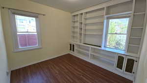Bedroom featuring a healthy amount of sunlight, baseboards, and dark wood-style flooring