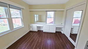 Bedroom with plenty of natural light, baseboards, built in desk, and dark wood-type flooring