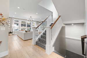 Stairs featuring wood finished floors, recessed lighting, and a notable chandelier