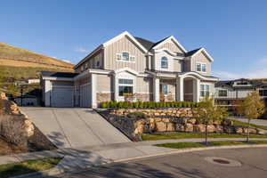 Craftsman inspired home featuring board and batten siding, stone siding, a garage, and concrete driveway