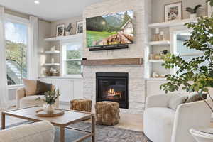 Living area with recessed lighting, wood finished floors, a stone fireplace, and built in features