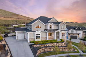 View of front of property featuring board and batten siding, driveway, stone siding, and a porch