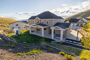 Rear view of property with a residential view, a mountain view, a lawn, a patio, and stucco siding