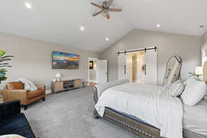 Carpeted bedroom with high vaulted ceiling, a barn door, baseboards, visible vents, and recessed lighting