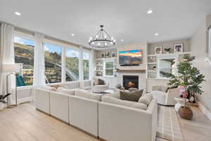 Living area featuring light wood-style flooring, an inviting chandelier, a fireplace, baseboards, and recessed lighting