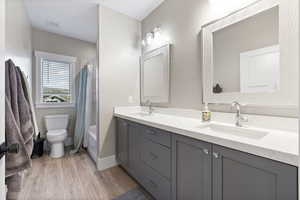 Bathroom featuring toilet, wood finished floors, a sink, and visible vents