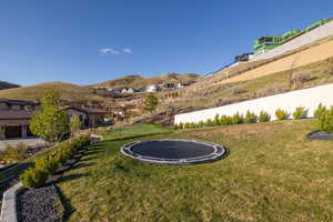 View of yard featuring a mountain view, fence, and a trampoline