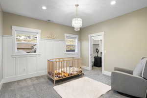 Carpeted bedroom featuring wainscoting, recessed lighting, a chandelier, a closet, and a decorative wall