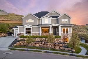 Craftsman-style home with board and batten siding, driveway, and stone siding
