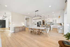 Dining space featuring light wood finished floors, baseboards, recessed lighting, and a notable chandelier