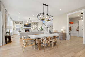 Dining space with recessed lighting, light wood-style flooring, a large fireplace, and a chandelier