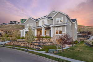 View of front facade with board and batten siding, stone siding, and a front lawn