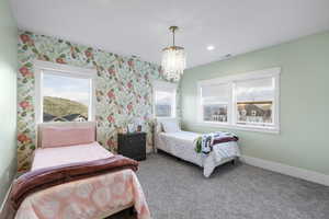 Bedroom featuring visible vents, baseboards, an inviting chandelier, carpet, and wallpapered walls