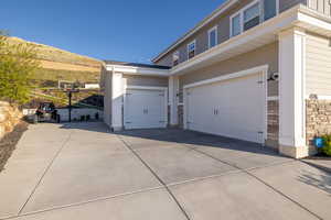 View of home's exterior featuring a garage, stone siding, and concrete driveway