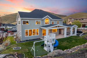 Rear view of property with a patio area, a lawn, a shingled roof, a mountain view, and stucco siding