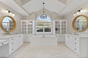Full bathroom featuring marble finish floor, lofted ceiling, two vanities, and a chandelier