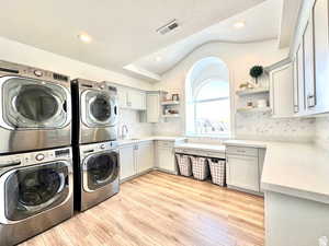 Laundry room featuring washing machine and dryer, cabinet space, stacked washing maching and dryer, and visible vents