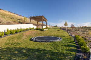 View of yard with fence, a pergola, and a trampoline
