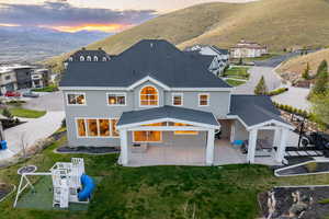 Rear view of house featuring a yard, stucco siding, a patio, roof with shingles, and a mountain view
