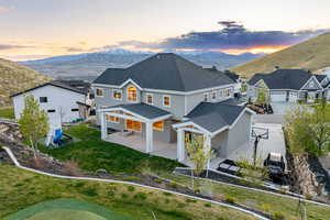 Rear view of property with a mountain view, a patio, stucco siding, roof with shingles, and a residential view