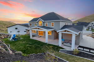 Rear view of house featuring a patio area, a playground, a yard, stucco siding, and roof with shingles