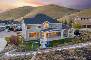 Back of house at dusk with a yard, a patio area, stucco siding, and a mountain view