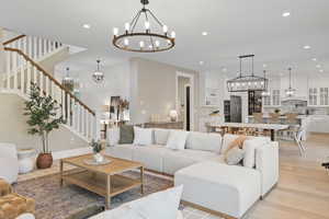 Living room with stairway, a notable chandelier, light wood finished floors, and recessed lighting