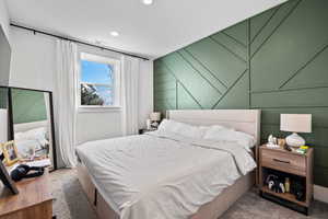 Carpeted bedroom featuring visible vents, recessed lighting, and a decorative wall