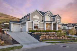 View of front of house featuring concrete driveway, stone siding, board and batten siding, and a garage