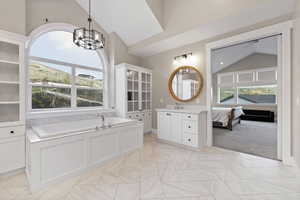 Full bath with vaulted ceiling, a bath, vanity, baseboards, and a notable chandelier