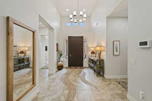 Foyer entrance with a chandelier, a high ceiling, baseboards, and recessed lighting