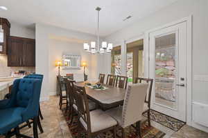 Dining room with visible vents, a notable chandelier, and light tile patterned floors