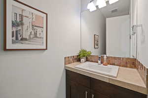 Bathroom with backsplash, vanity, and visible vents